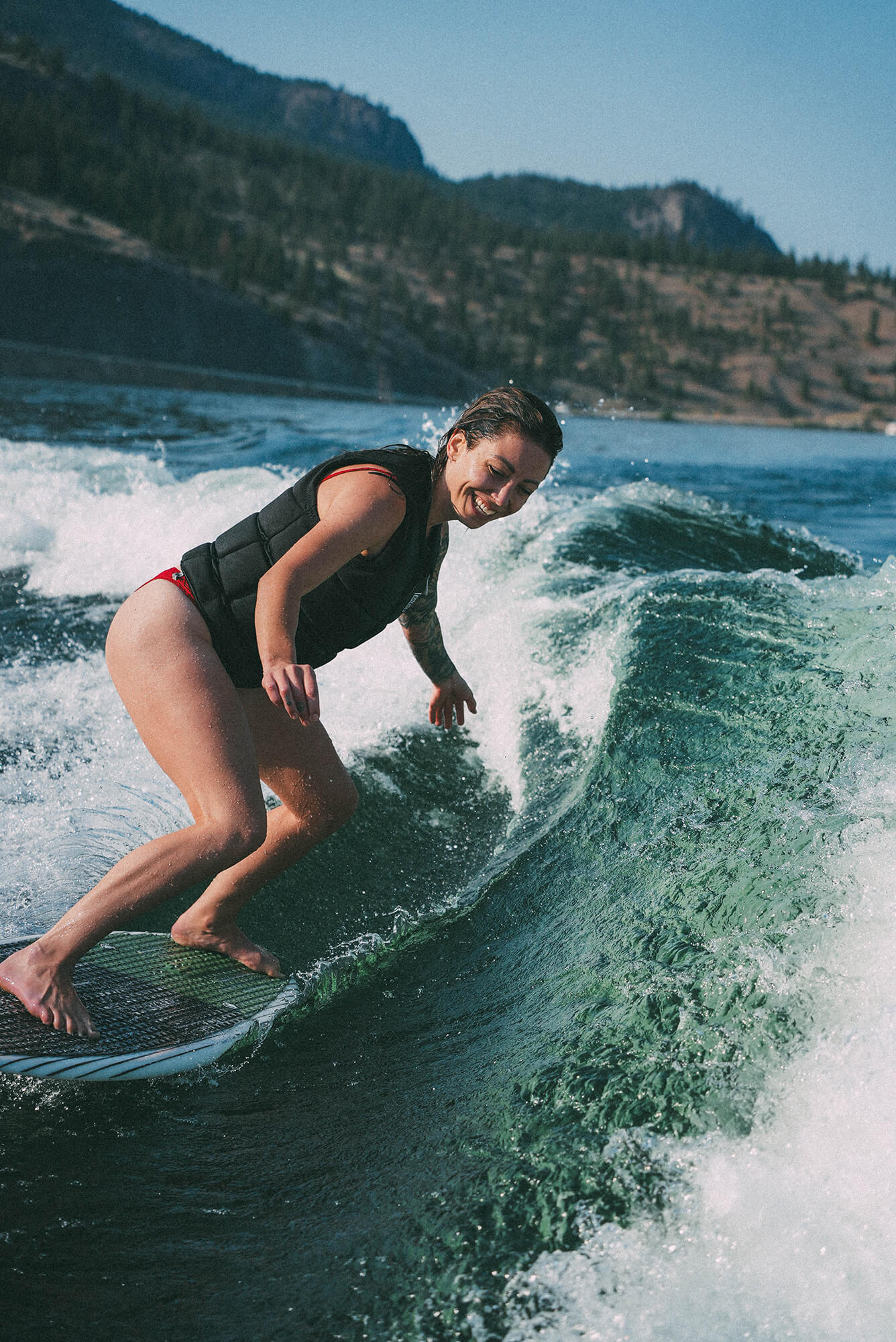 Amber Bahm wakesurfing on Okanagan Lake in Kelowna, BC with big smile on face